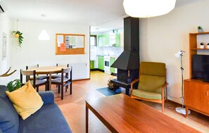 A living room with a sofa, a dining table, a green armchair, a fireplace, and a kitchen in the background. - 2 bedroom lovely home in Ekshärad (Ekshärad)