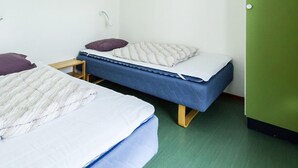 A room with two single beds, each with a pillow and a quilted blanket. There is a small wooden table between the beds. The room has a green floor and white walls. - Amazing home in Ekshärad with WiFi (Ekshärad)