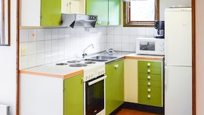 Une cuisine de taille réduite, équipée d’une cuisinière, d’un évier et d’un four à micro-ondes.