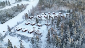 Un groupe de chalets en bois, nichés au cœur d’une forêt enneigée.