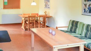 A room with a wooden table, chairs, a sofa, a bulletin board, and a poster on the wall. - 2 bedroom nice home in Ekshärad (Ekshärad)