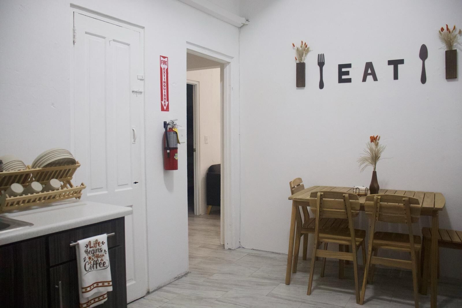 A kitchen with a dining table and chairs, a fire extinguisher, and a sign on the wall that says "FIRE EATING".