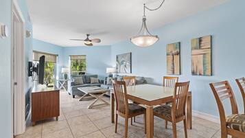 A dining area with a wooden table and chairs, a ceiling fan, and artwork on the walls.
