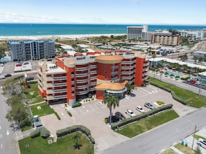 A multi-story hotel with a central courtyard, parking lot, and a view of the beach. - Beach Escape • Pool • Free Parking (Treasure Island)