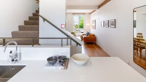A modern kitchen with a white countertop, a stainless steel sink, and a staircase with wooden steps and metal railings. - New York Loft | Private Car Park | Walk to Stadium (Christchurch)