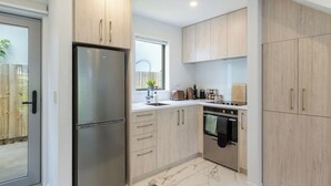 Una cocina moderna con armarios de madera clara, electrodomésticos de acero inoxidable y piso de mármol.