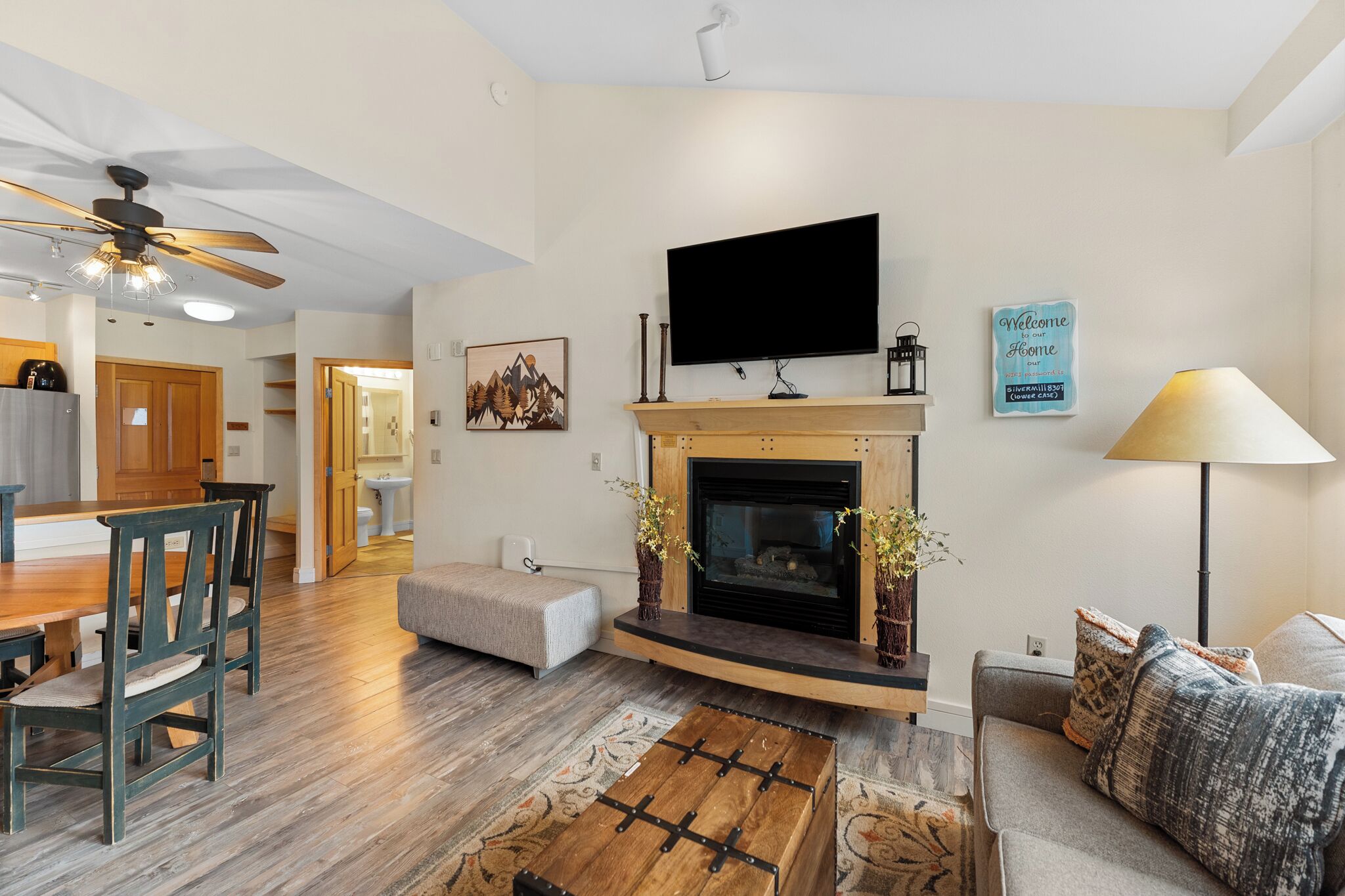 A living room with a fireplace, a television, and a dining area with wooden furniture.
