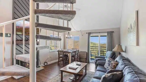 A spacious living area with a sofa, coffee table, and a dining table. A spiral staircase leads to an upper level. - Beautiful 3-bedroom apt Skiview drive, 10 minutes to Gatlinburg (Gatlinburg)