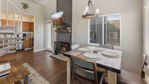 A spacious living area with a fireplace, dining table set for four, and a kitchen in the background. - Beautiful 3-bedroom apt Skiview drive, 10 minutes to Gatlinburg (Gatlinburg)