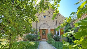 Un edificio in pietra con un vialetto sterrato che conduce a una porta in legno.