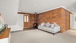 A modern living room with a white sofa, a brick accent wall, and a fireplace. - Manyana Joyful Escape (Manyana)