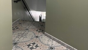 A hallway with a tiled floor, a staircase, and a framed painting of flowers. - A cosy space Hollywood unit with walking distance to Sunset Blvd (Los Angeles)