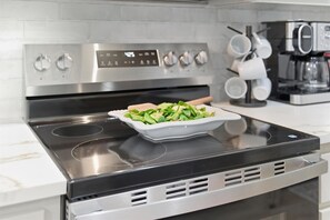 A kitchen with a modern stove, a digital oven control panel, and a coffee maker. - Pearl of the West - Your Abilene Gem (Abilene)
