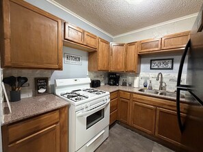A kitchen with wooden cabinets, a white stove, a sink, and a refrigerator.