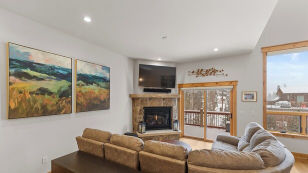 A modern living room with a fireplace, a flat-screen TV, and large windows offering a view of the outside. - A736-3 (Keystone)
