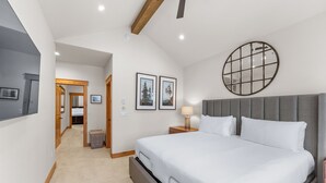 A modern hotel room with a large bed, a round mirror, and framed pictures on the wall. - A736-3 (Keystone)