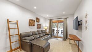 A modern living room with a sectional sofa, a wooden ladder, a TV, and a table. - A736-3 (Keystone)