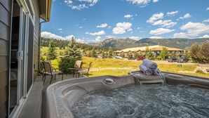 Ein Whirlpool mit Blick auf die Berge, Gartenmöbel und ein klarer Himmel.