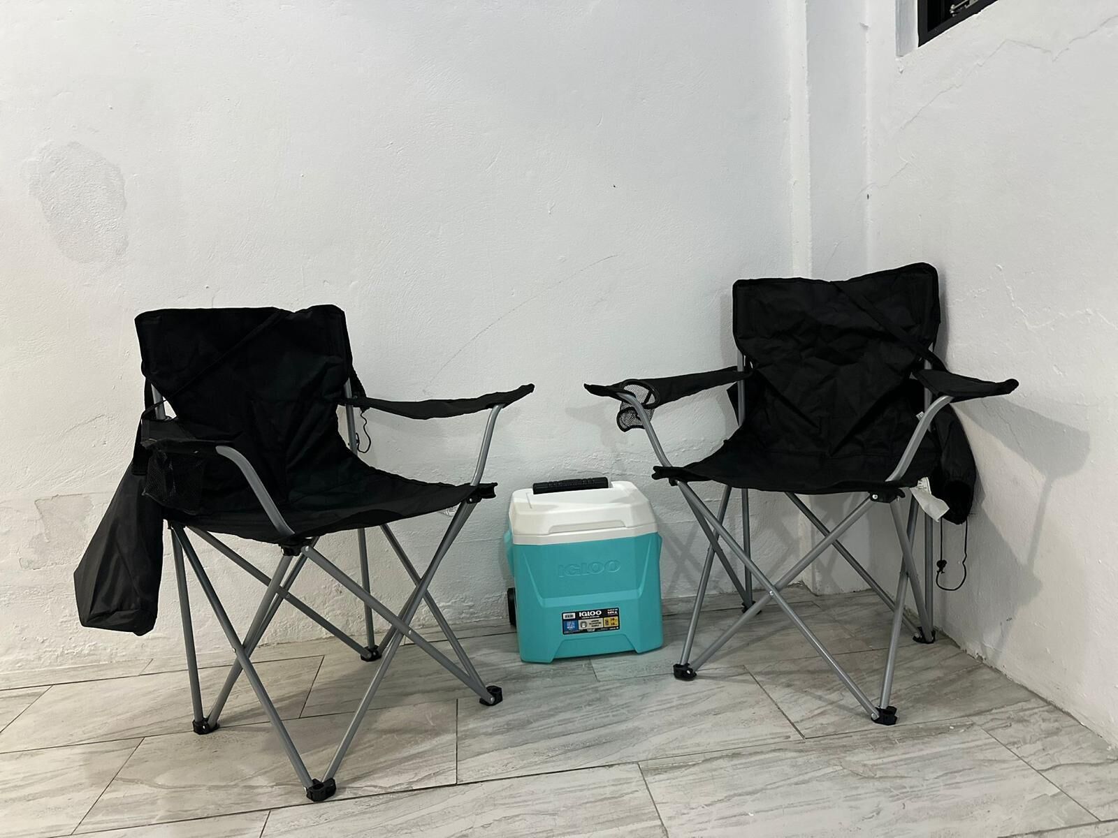 Two black folding chairs with a blue cooler between them.