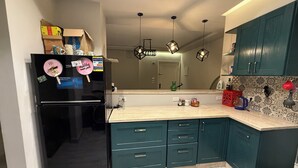 Eine moderne Küche mit türkisfarbenen Schränken, einem schwarzen Kühlschrank und einer hellen Arbeitsplatte.