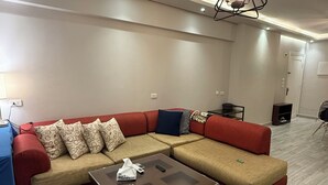 Ein modernes Wohnzimmer mit einem Ecksofa, einem Glastisch und einer Pendelleuchte.