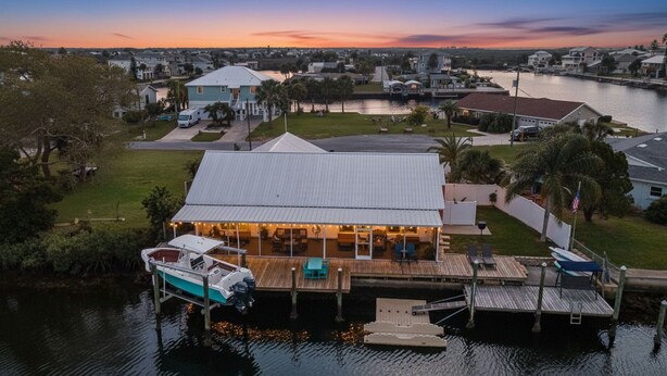 A waterfront property with a dock, a boat, and a house with a covered patio. - Beautiful 3BR/2BA - Steps from the Gulf & FREE Boat ramp - Kayaks & bikes incl. (Hernando Beach)