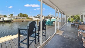 A covered outdoor area with a view of the water and boats, featuring chairs and a sofa. - Beautiful 3BR/2BA - Steps from the Gulf & FREE Boat ramp - Kayaks & bikes incl. (Hernando Beach)