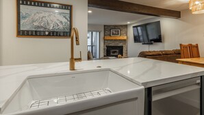 A modern kitchen with a white marble countertop, a built-in sink, and a wooden ceiling beam. - Chamonix 35: Beautiful Upgrades, Walk to Lifts (Mammoth Lakes)