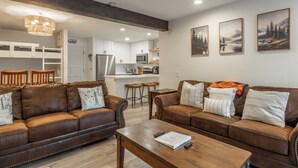A modern living room with two brown leather sofas, a wooden coffee table, and a kitchen in the background. - Chamonix 35: Beautiful Upgrades, Walk to Lifts (Mammoth Lakes)