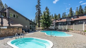 A pool area with two oval pools, stone walls, and a stone fence. - Chamonix 35: Beautiful Upgrades, Walk to Lifts (Mammoth Lakes)
