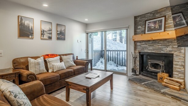 A living room with a brown leather sofa, a wooden coffee table, and a stone fireplace. - Chamonix 35: Beautiful Upgrades, Walk to Lifts (Mammoth Lakes)