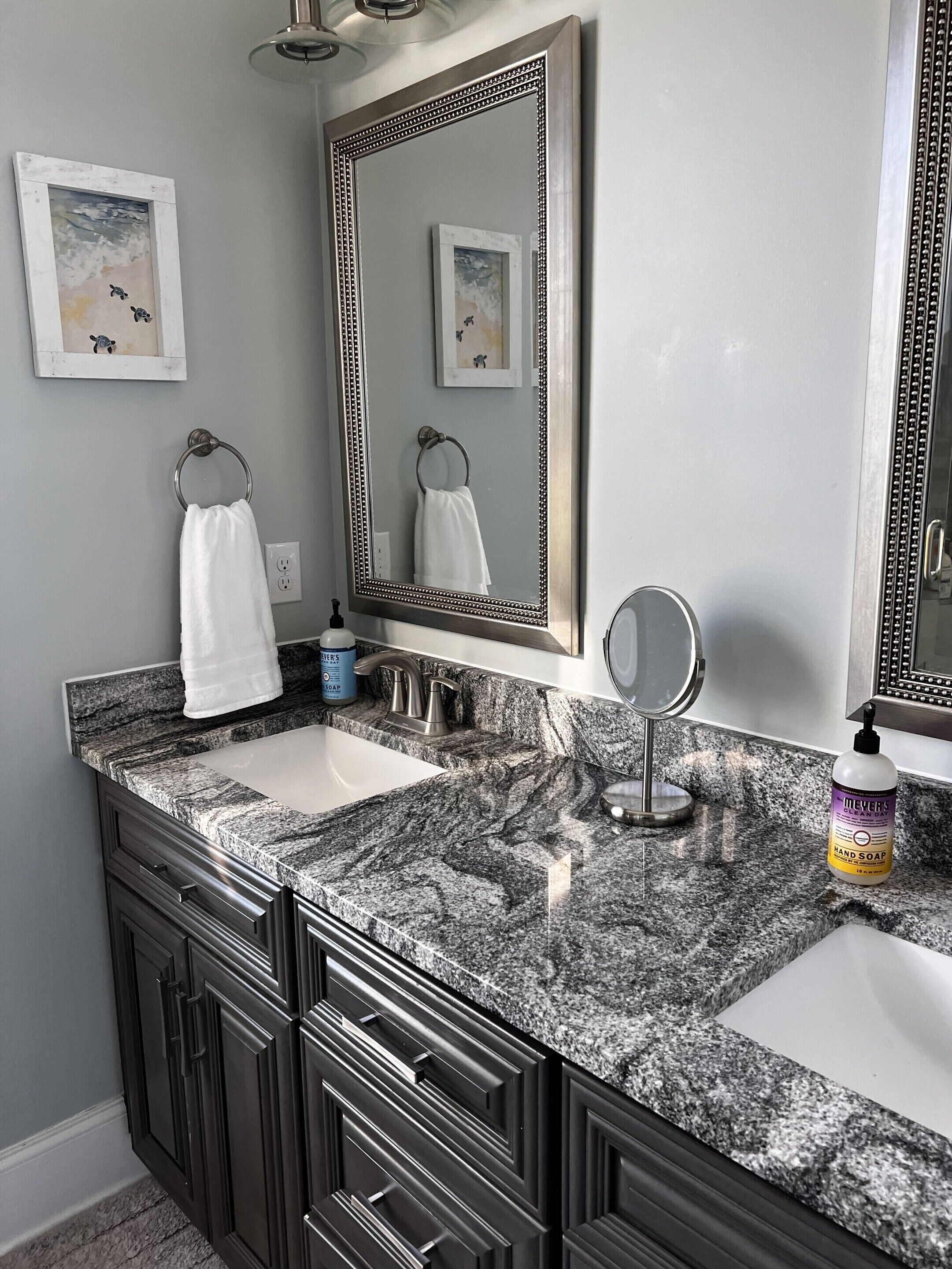A bathroom with two sinks, a large mirror, and a cabinet with drawers.