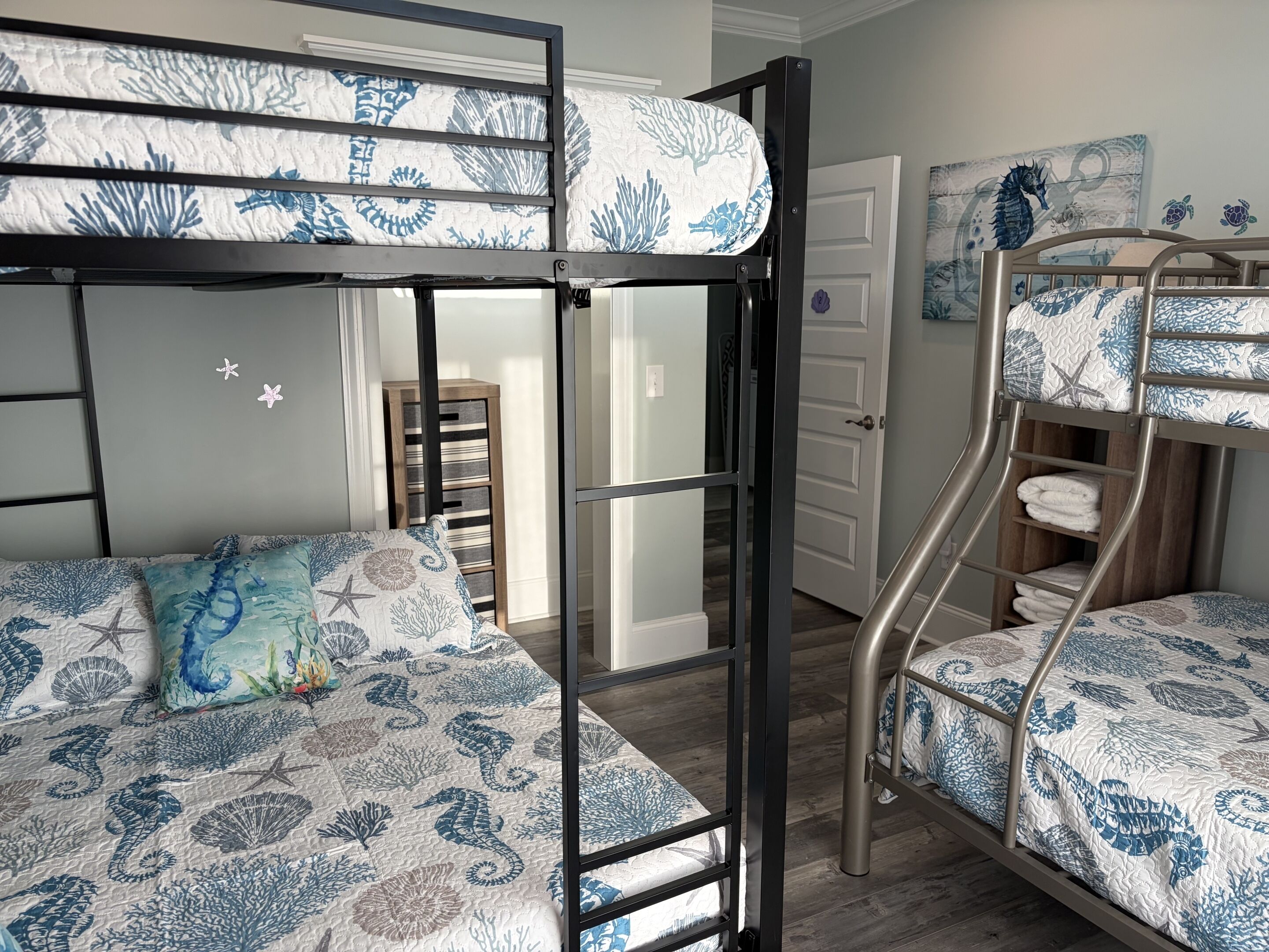 A bunk bed room with a nautical theme, featuring starfish and seahorse patterns on the bedding.