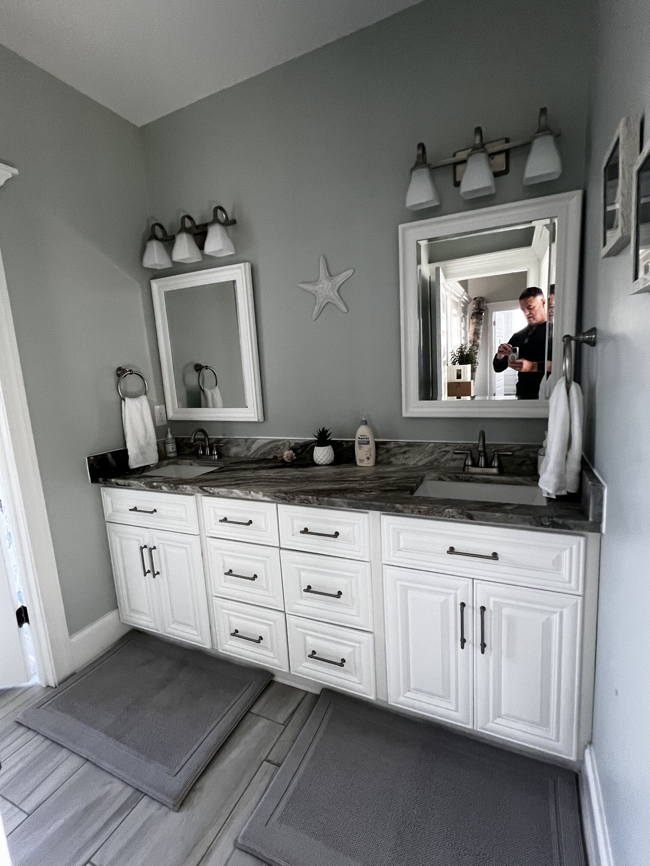 A bathroom with a double vanity, two mirrors, a star decoration, and a towel rack.