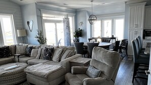 A spacious living room with a sectional sofa, a chaise lounge, and a dining area with a table and chairs. - Top Sail Beach Sunsets (Sneads Ferry)