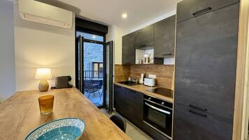 Una cocina moderna con armarios oscuros, encimera de madera y zona de comedor con mesa y sillas.