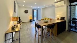 A modern kitchen with a wooden dining table, bar stools, and a built-in oven. - Magnifique T3 tout confort (PROPRIANO)