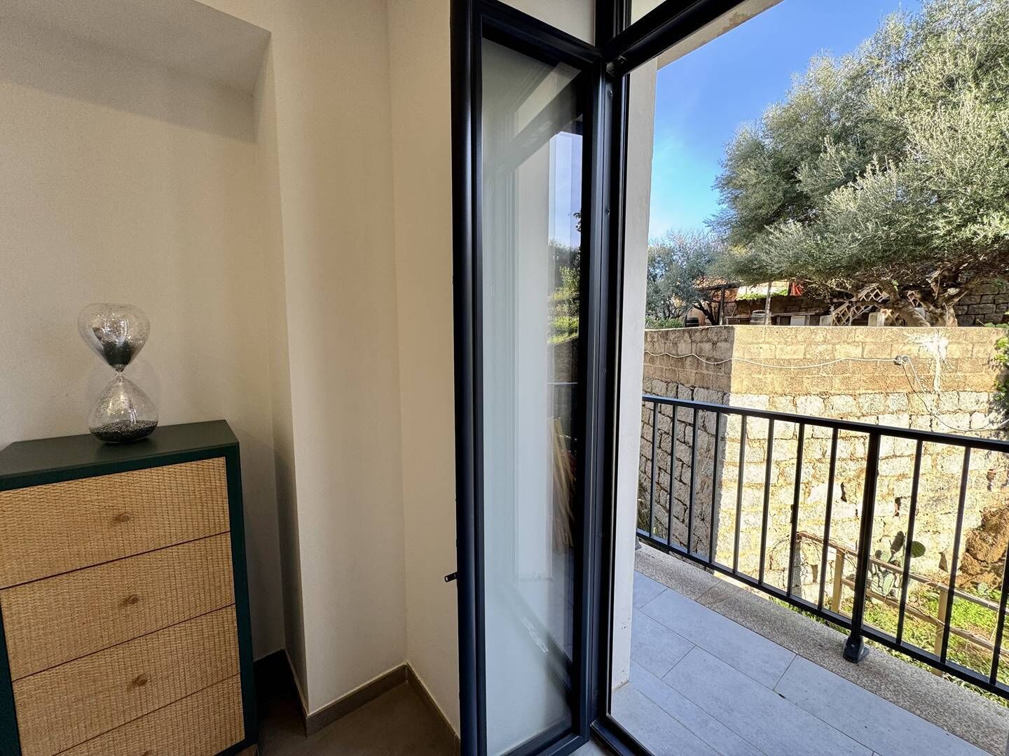 En balkon med udsigt over en have og en stenvæg.