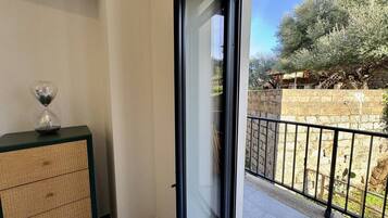En balkon med udsigt over en have og en stenvæg.