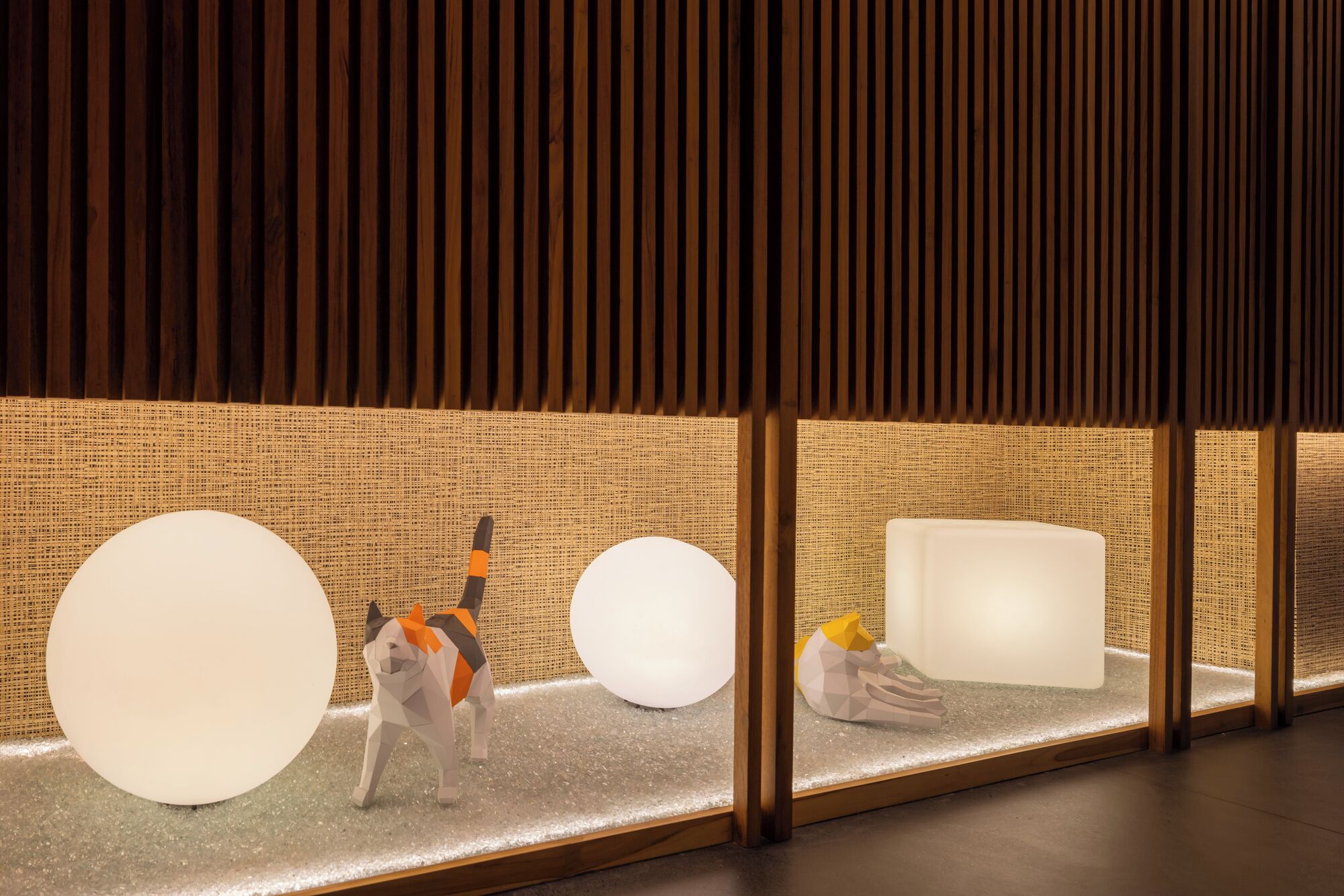 A modern interior with wooden slats, a textured wall, and geometric sculptures.