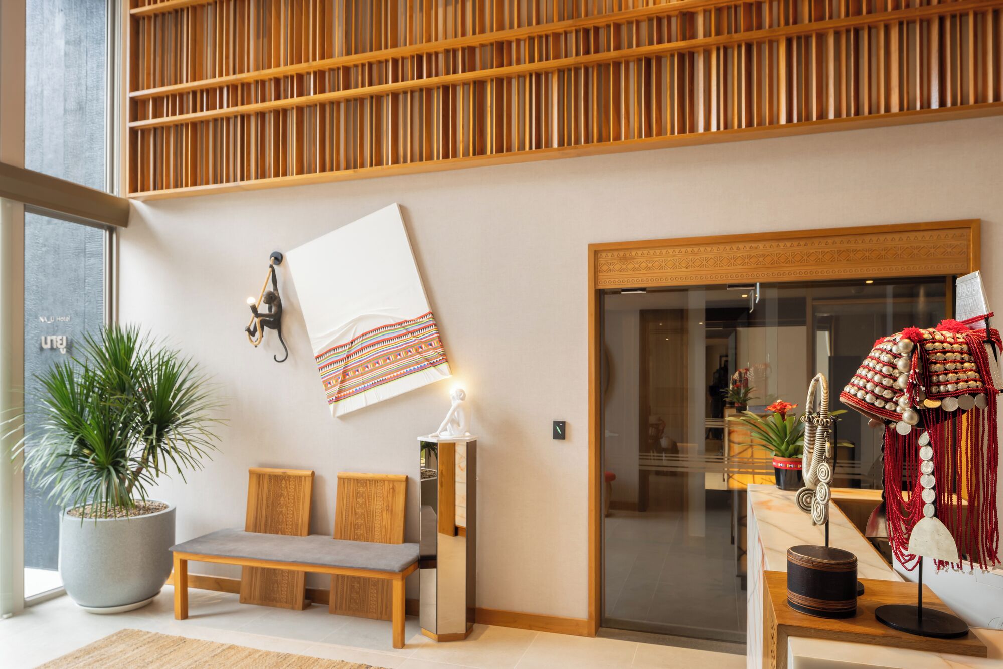 Un interior moderno con techo de listones de madera, un banco, una lámpara de pared y un adorno en la pared.