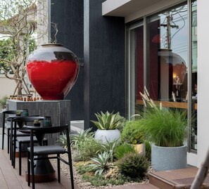 An outdoor seating area with black chairs and a large red spherical planter. - Na U Hotel (Chiang Mai)