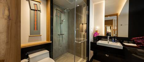 A modern bathroom with a glass-enclosed shower, a toilet, and a vanity with a mirror.