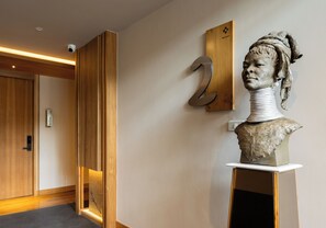 Un interior moderno con una puerta de madera, un cartel con número y una escultura de busto.