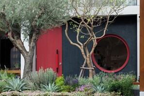 A tree with a red door and a circular window in the background. - Na U Hotel (Chiang Mai)
