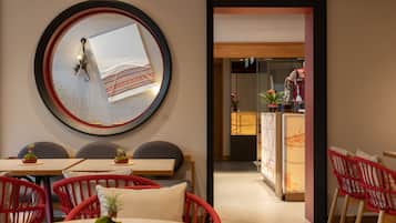 A modern interior with a round mirror, red wicker chairs, and a dining area.