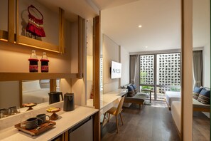 A modern hotel room with a kitchen area, a dining table, a sofa, and a large window with a view. - Na U Hotel (Chiang Mai)