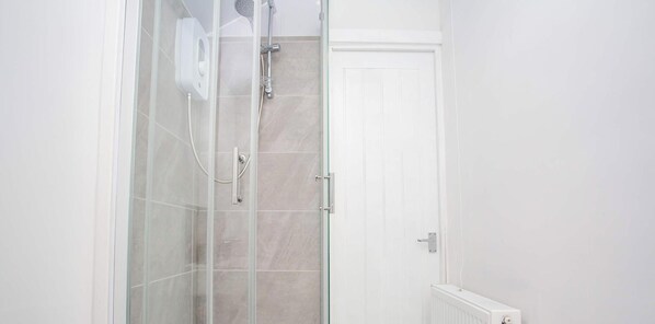 Eine Duschkabine mit Handbrause und am Wand montiertem Wasserhahn.