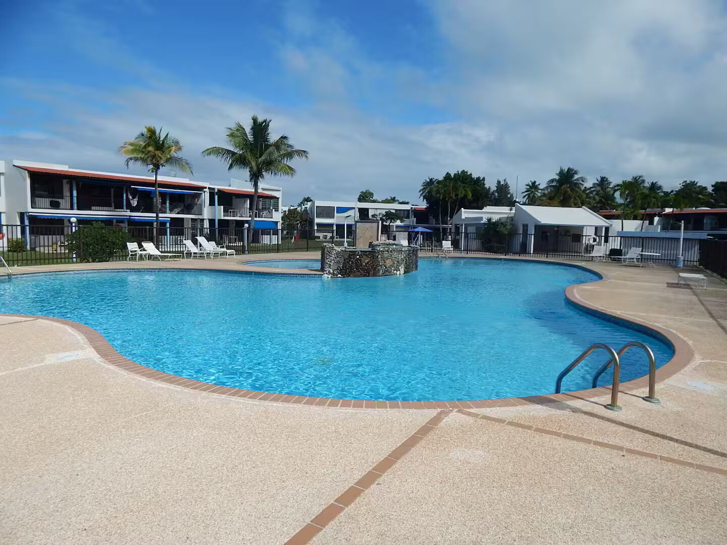 A swimming pool with lounge chairs and a stone feature in the center.