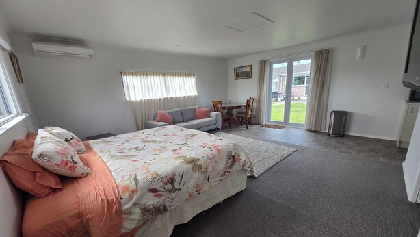 Un dormitorio con cama, sofá, mesa de comedor y televisor.
